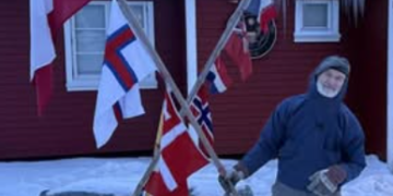 Legendary explorer Jens Kjeldsen holding flags during a protest in Nuuk, Greenland